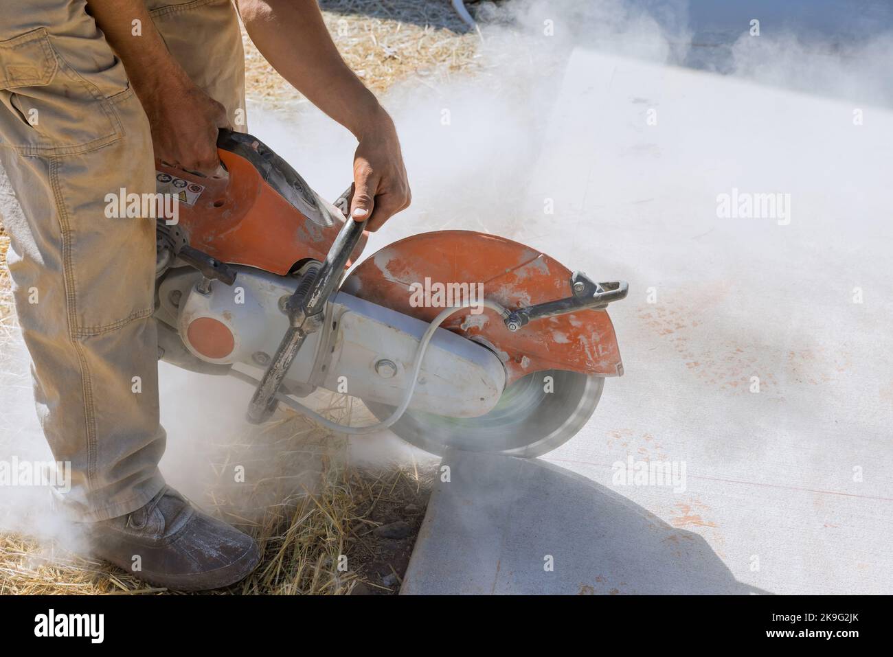 Construction worker cutting concrete paving stabs for sidewalk using cut off diamond bladed saw. Stock Photo