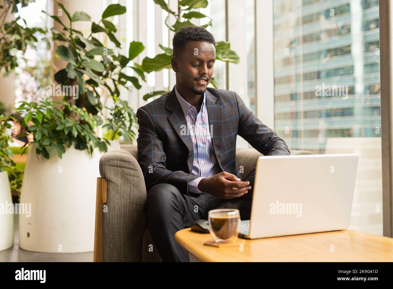 Portrait of African businessman sitting in coffee shop using laptop computer Stock Photo