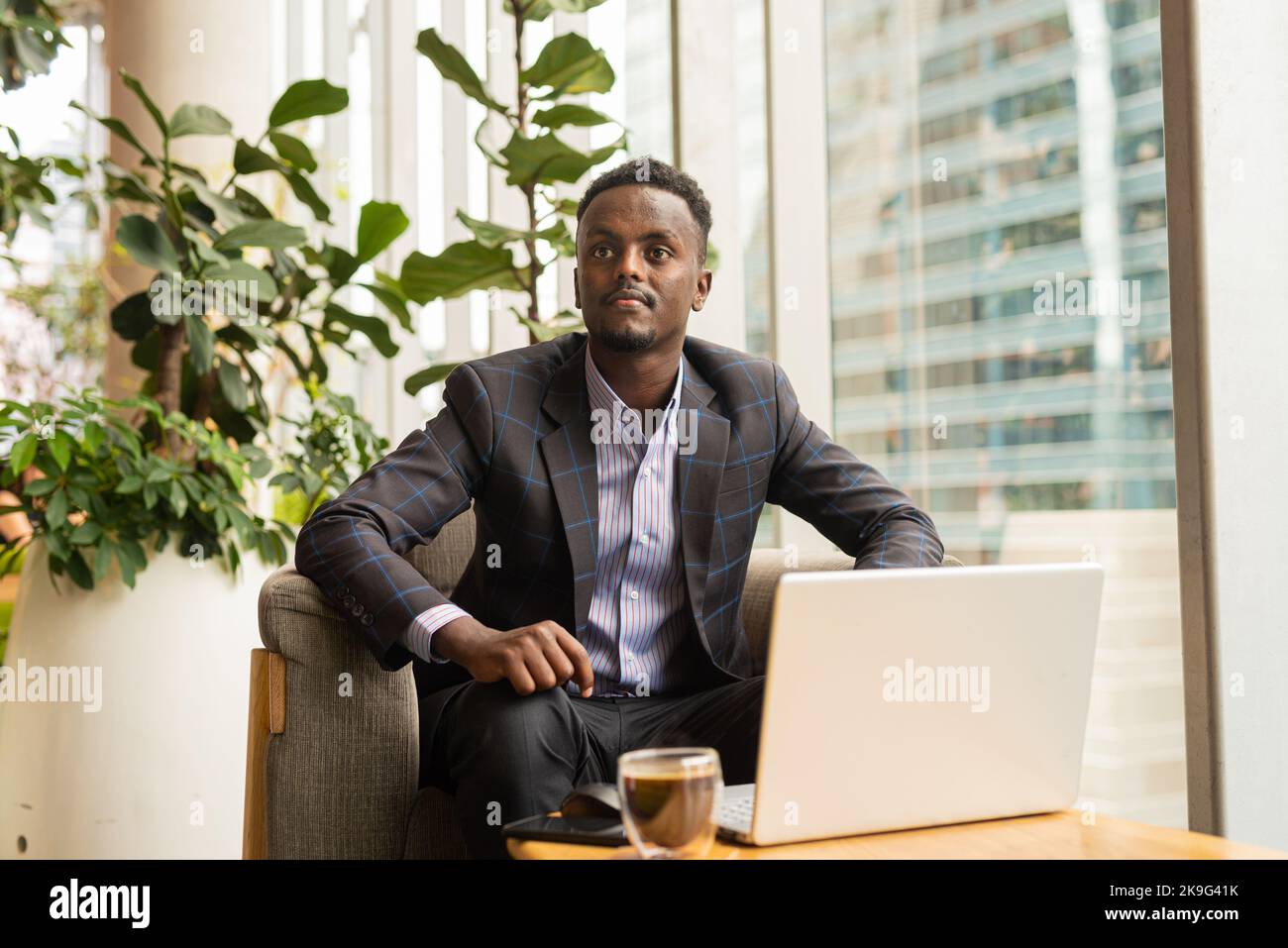 Portrait of African businessman sitting in coffee shop using laptop computer Stock Photo