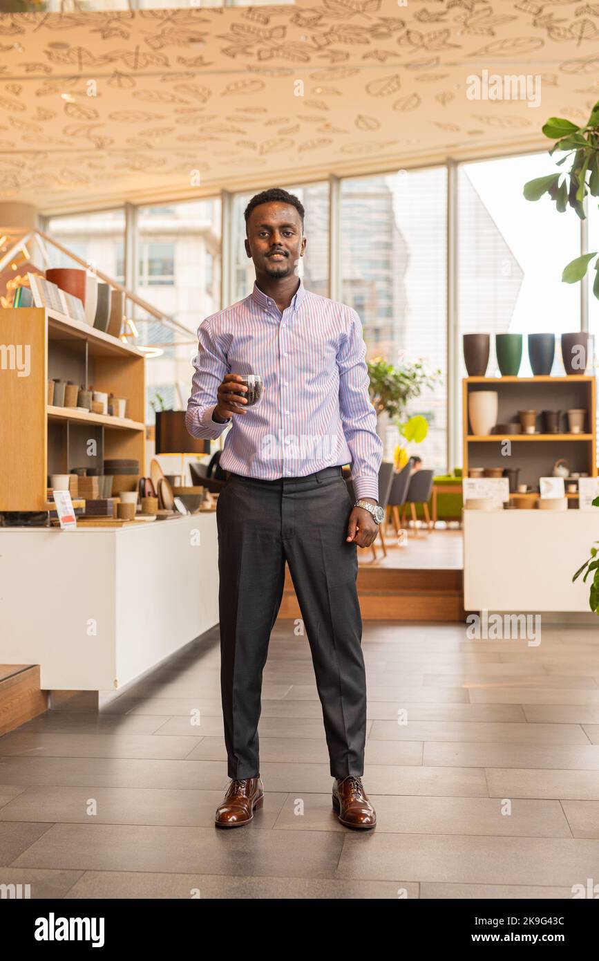 Full length portrait of African businessman indoors at coffee shop Stock Photo