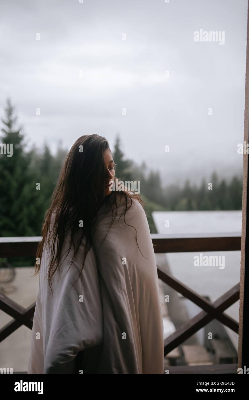 Young woman wrapped in a blanket on the balcony Stock Photo - Alamy
