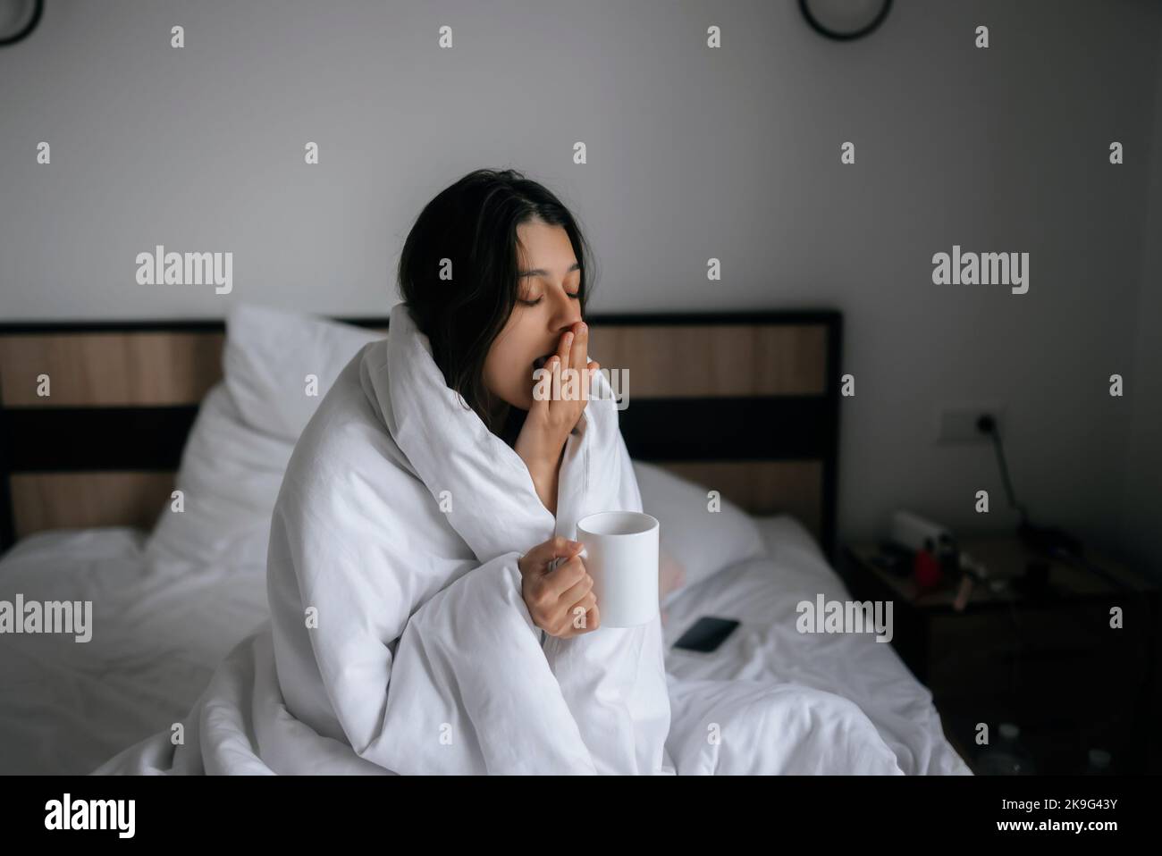 Woman wrapped in a blanket and holds a mug Stock Photo