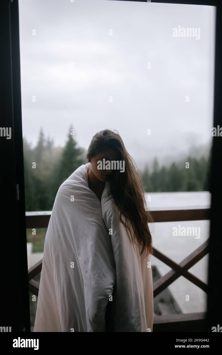 Young woman wrapped in a blanket on the balcony Stock Photo - Alamy
