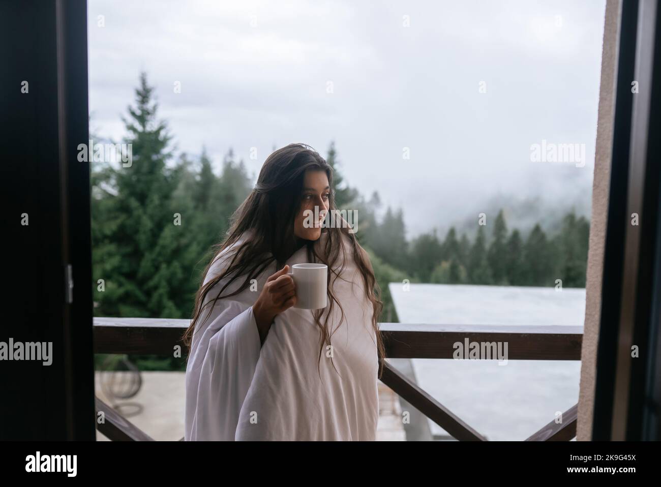Woman drinking tea on cozy balcony of a country house. Stock Photo