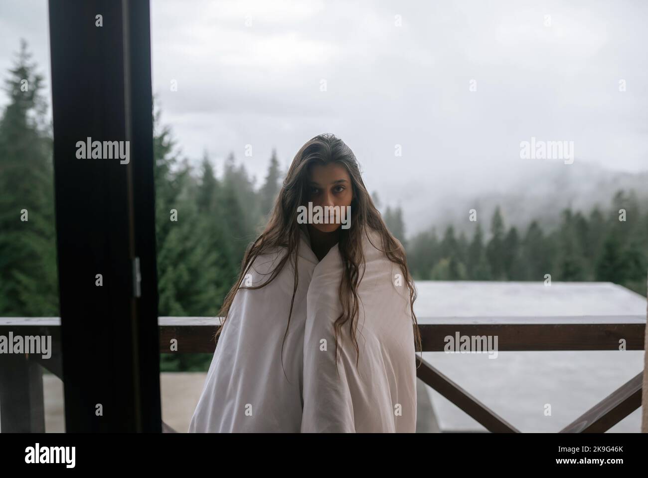 Young woman wrapped in a blanket on the balcony Stock Photo - Alamy