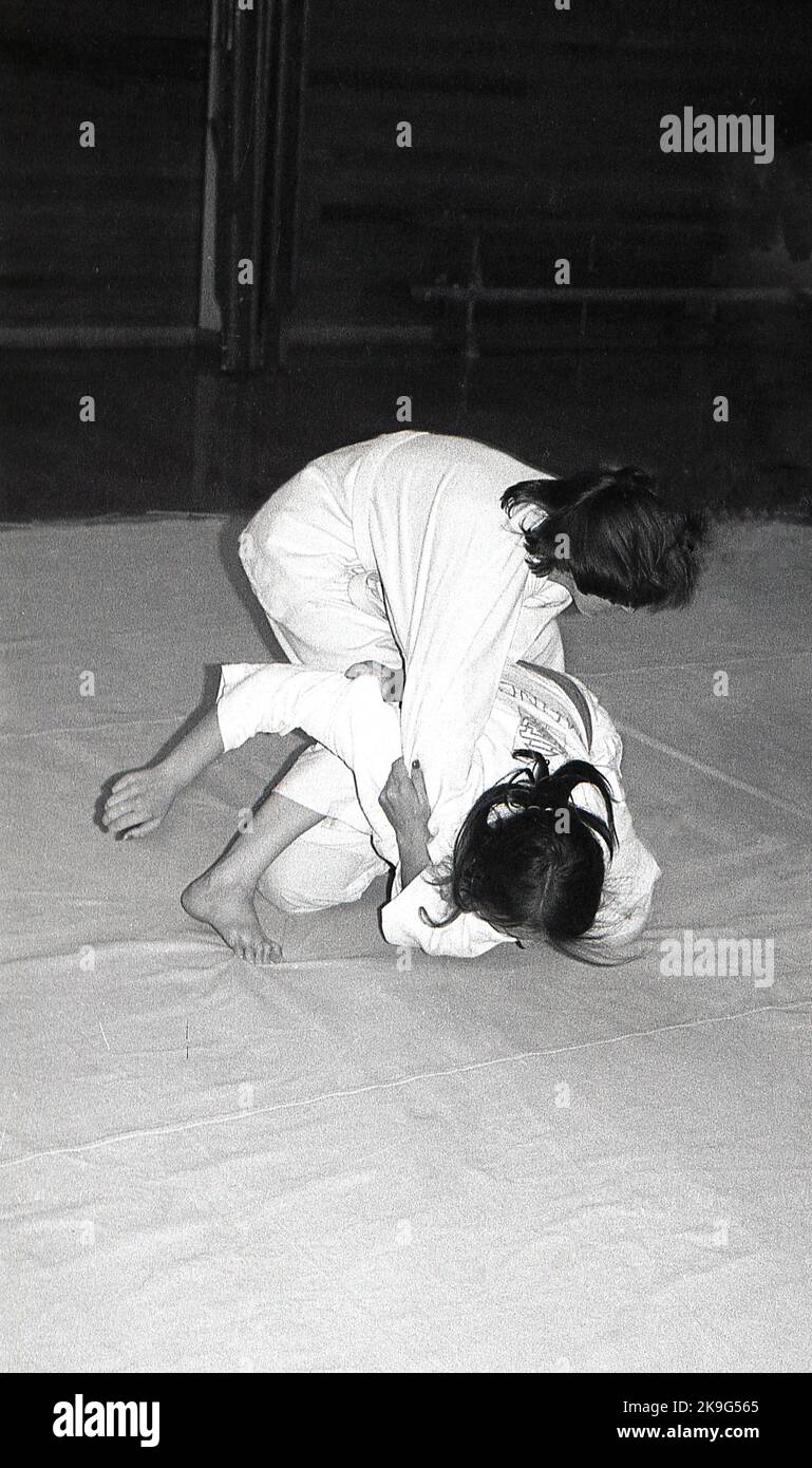1970s, historical, inside, on a mat, two girls competing in the sport of judo, a physical activity that involves two people wrestling and trying to throw each other to the ground. Judo is a Japanese word meaning 'art of gentleness' and derives from the ancient Japanese martial art of jujitsu. Stock Photo