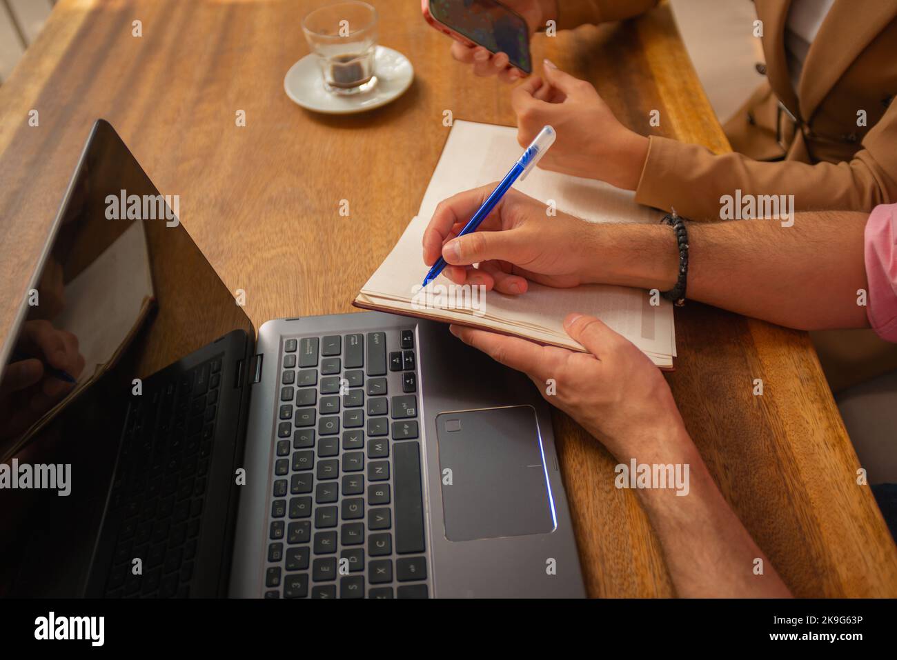 A business male is writing notes down that his colleague is giving to ...