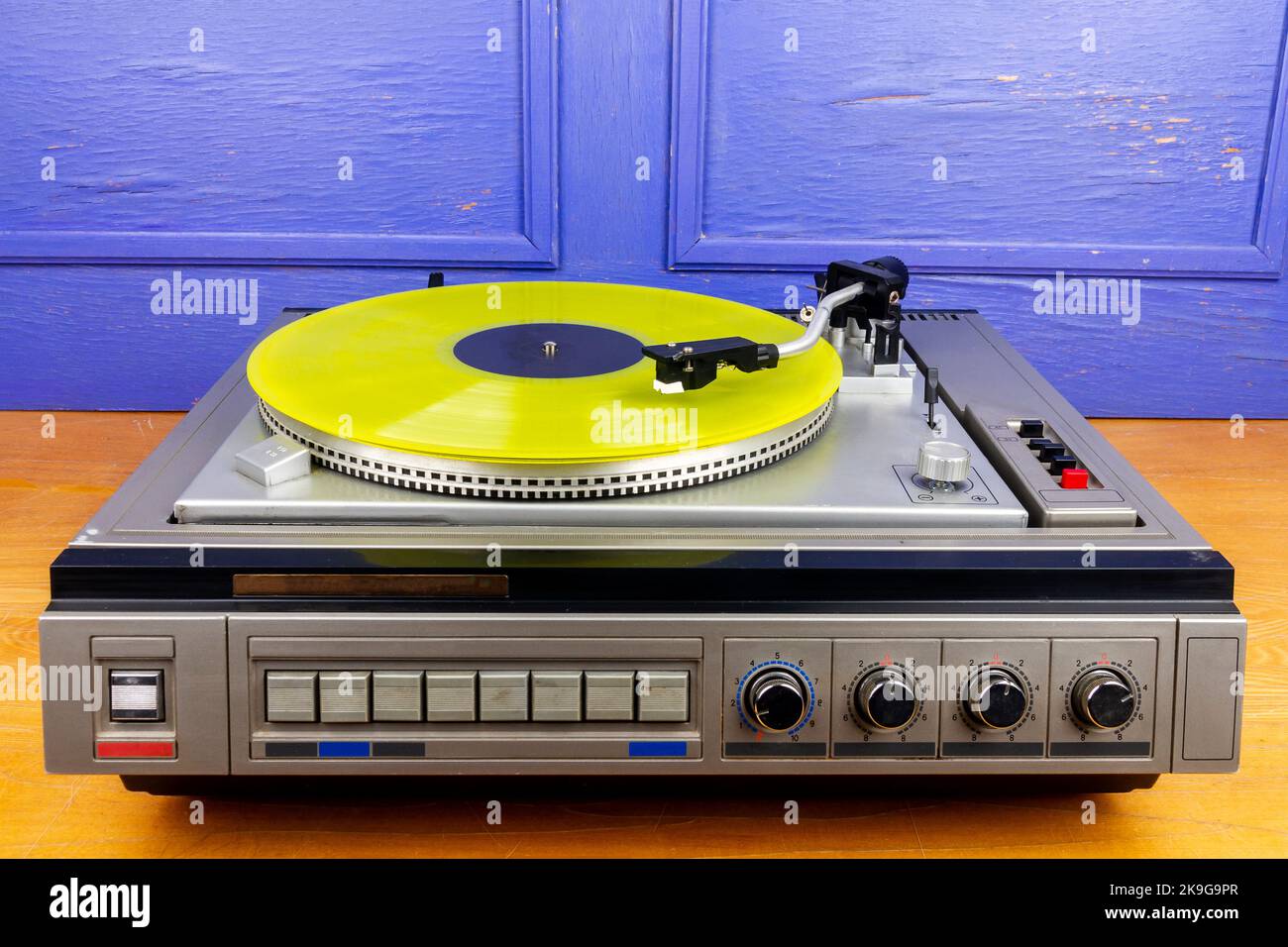 Vintage turntable vinyl record player with yellow vinyl on a table ...