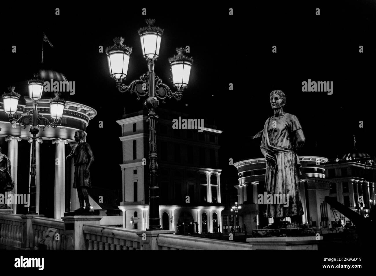 Statues decorating the Bridge of Civilisations, in front of Archaeology Museum, Skopje, North Macedonia. At night with lamp posts illuminating bridge. Stock Photo