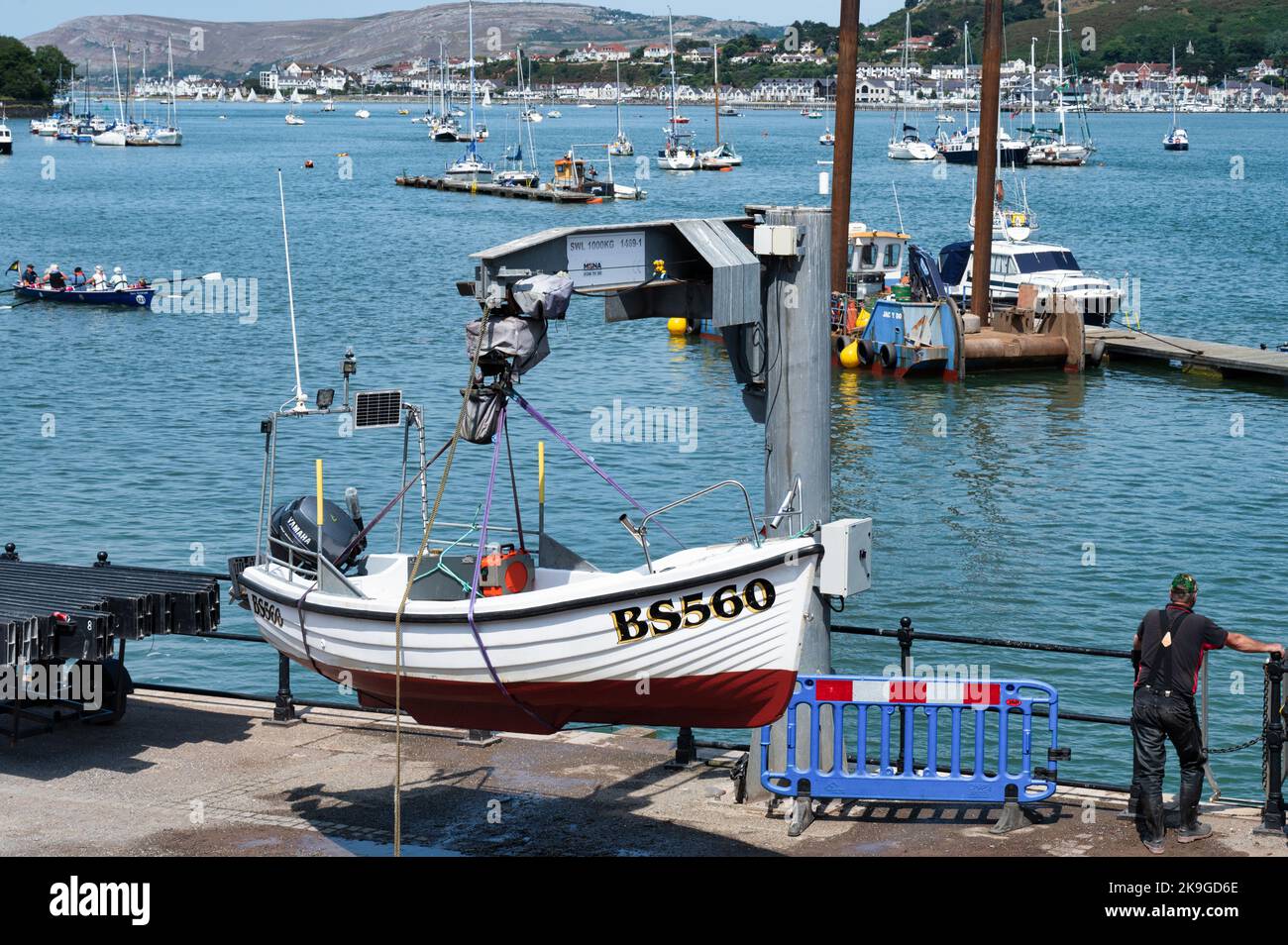 Conwy, UK- July 16, 2022: A small fishing boat getting lifted out of the water at Conwy harbor in the village of Conwy, Northern Wales. Stock Photo