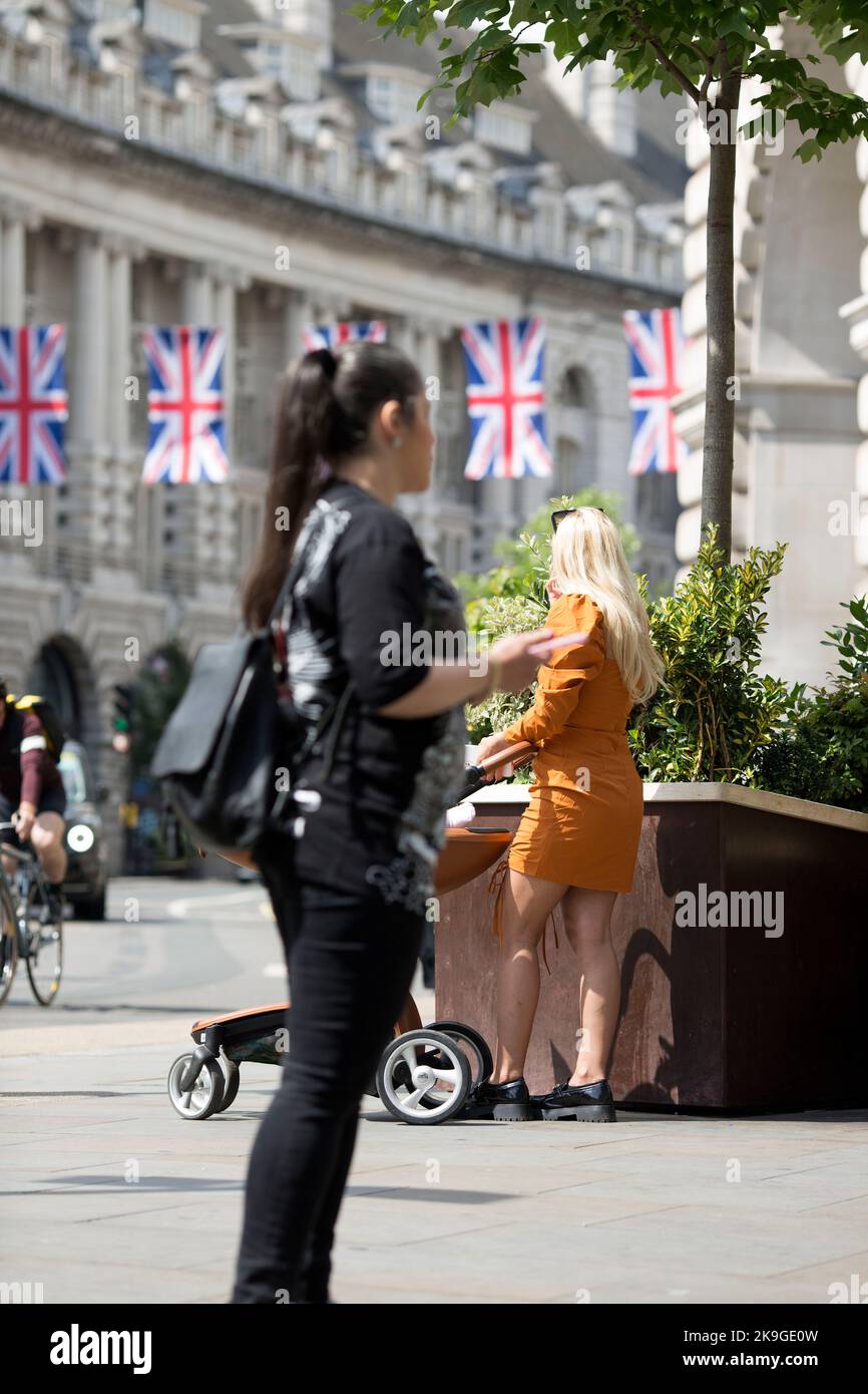 Back-dropped by Union flags, people gather near Piccadilly Circus, central London, on the first day of the Platinum Jubilee weekend. Stock Photo
