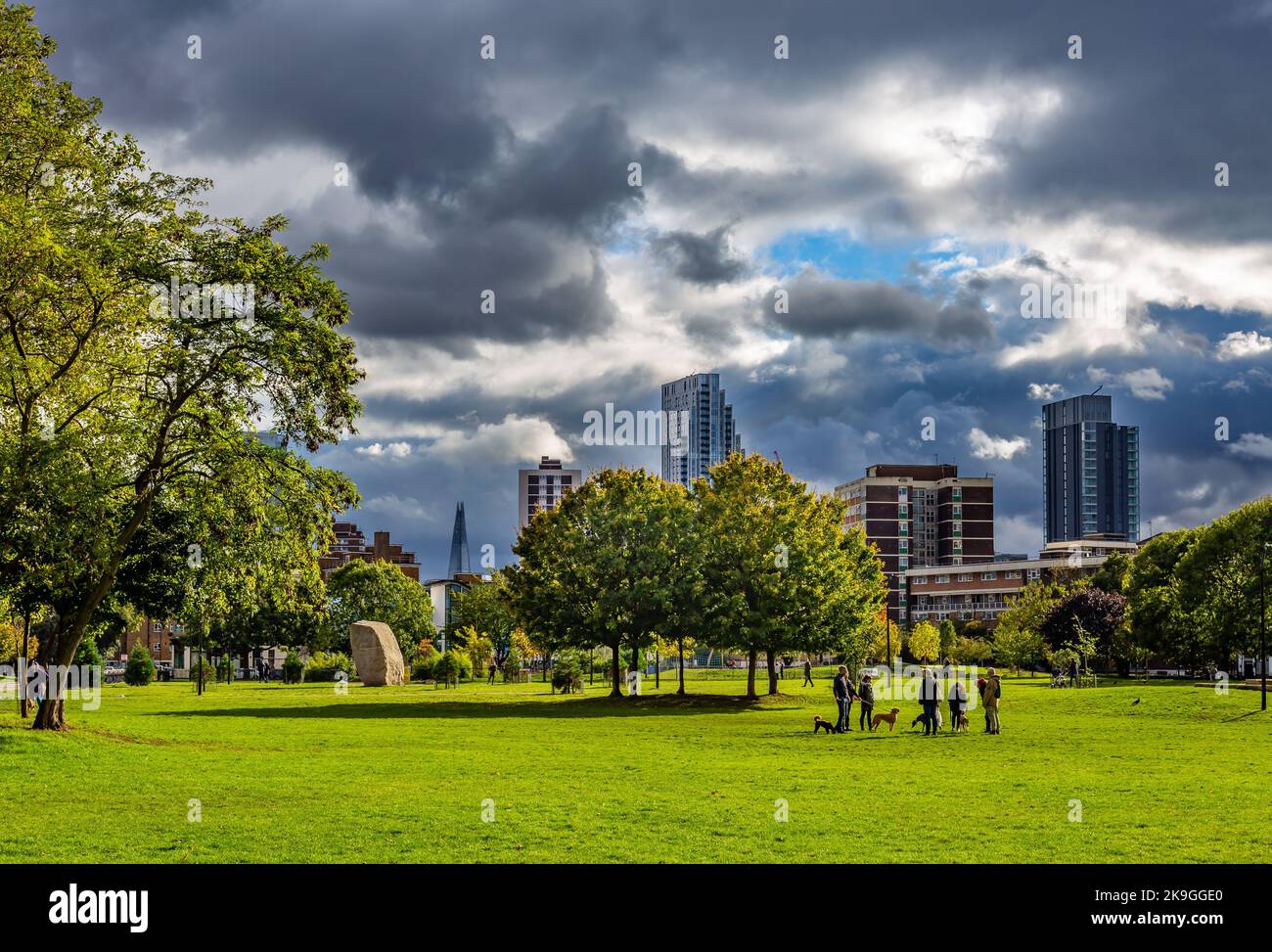 London has many open spaces such as this bordering on the City of London.Shoreditch park seen here looking towards ominous clouds and skyscrapers Stock Photo