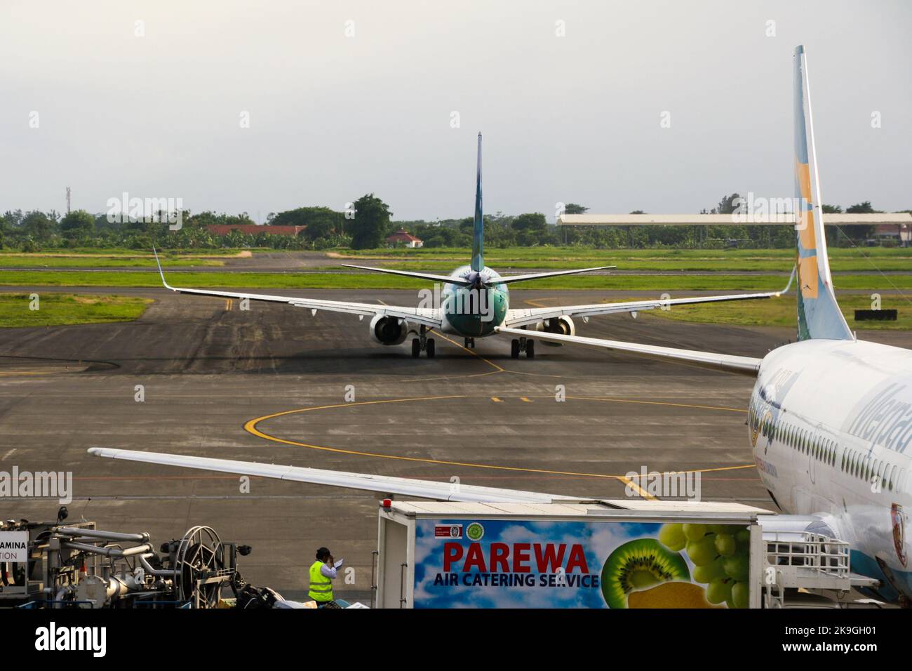 View of Garuda Indonesia airliner on runway at Juanda International Airport with clouds in blue