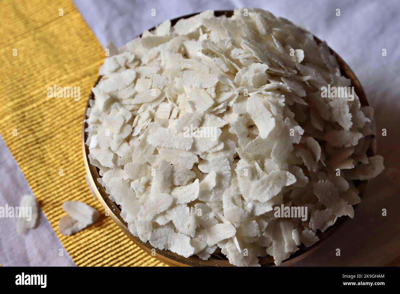 Close-up of  raw poha/beaten rice/flattened rice in a brass Uruli/vessel Stock Photo