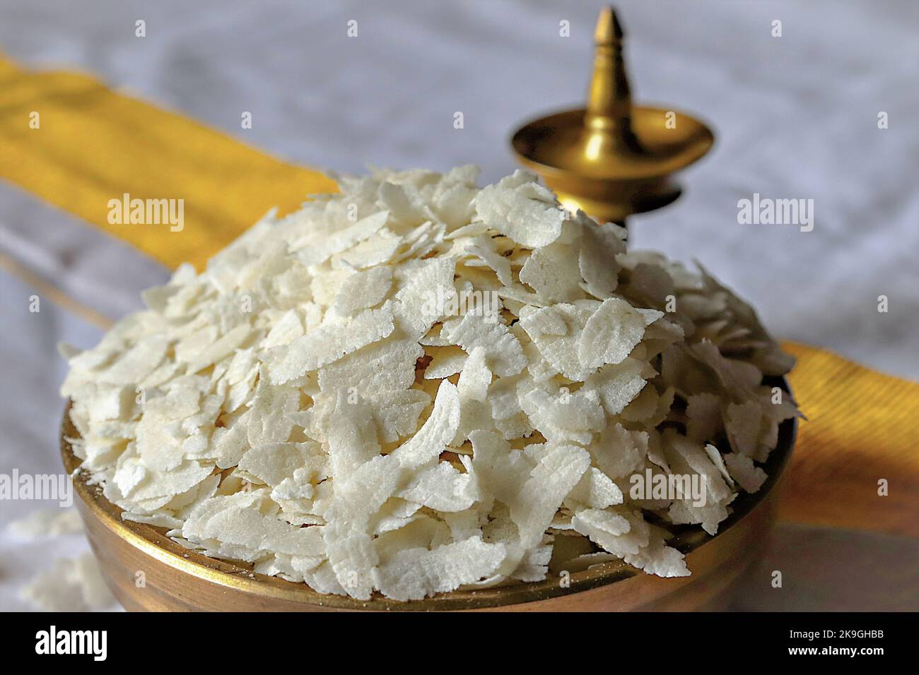 Close-up of  raw poha/beaten rice/flattened rice in a brass Uruli/vessel/brass oil lamp Stock Photo