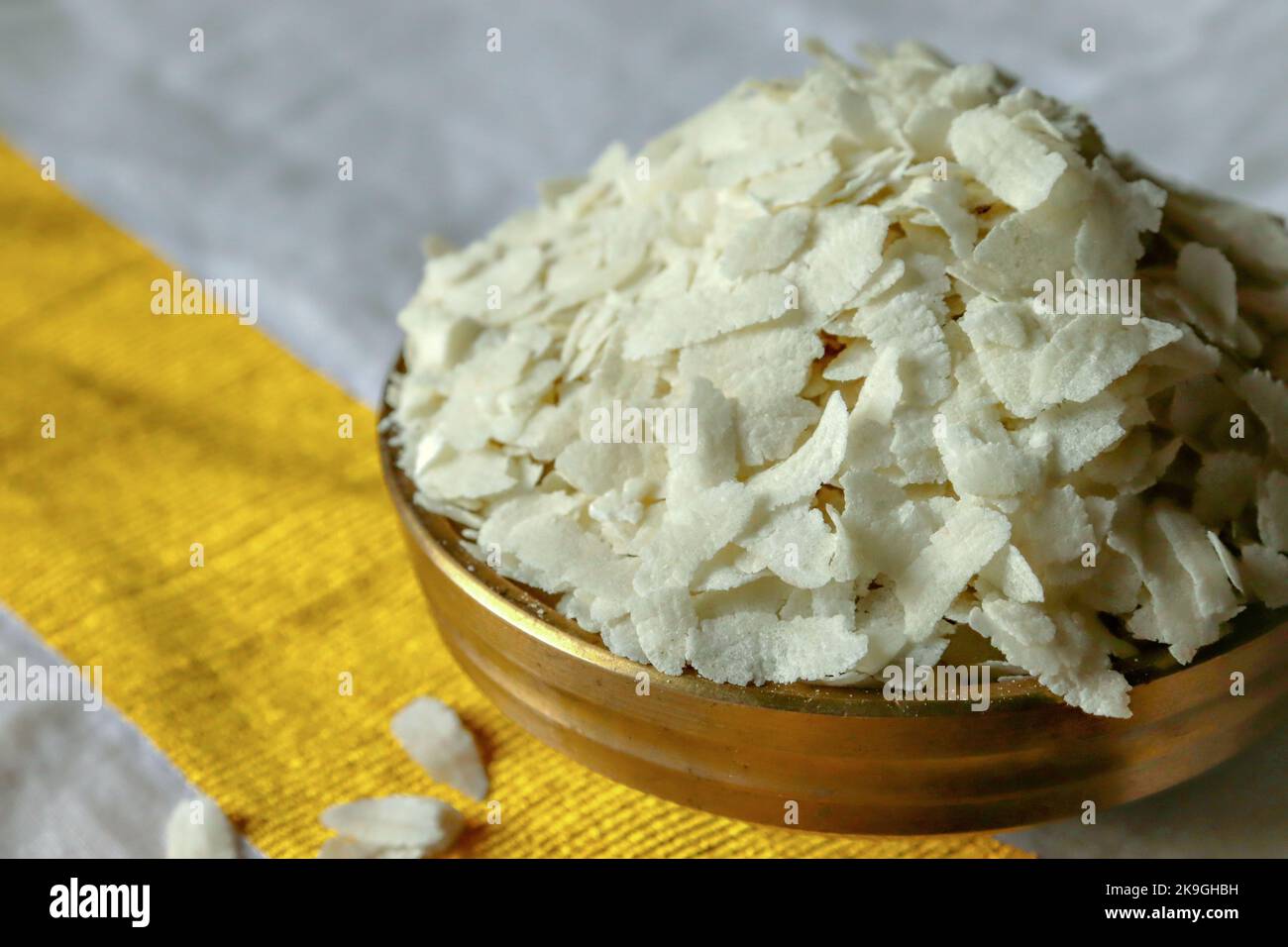 Close-up of  raw poha/beaten rice/flattened rice in a brass Uruli/vessel Stock Photo
