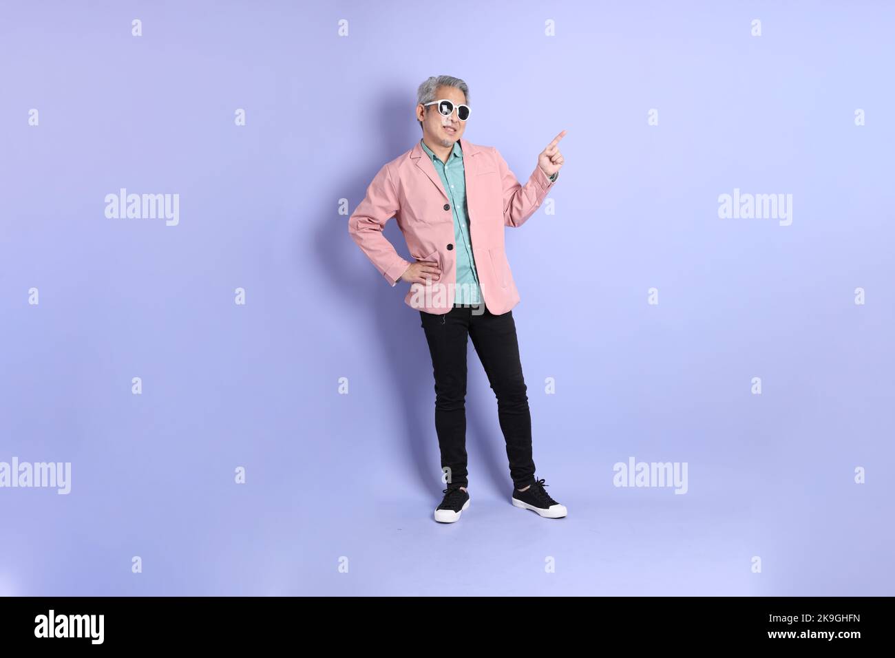 The 40s adult Asian man stnading on the purple background with smart casual clothes. Stock Photo