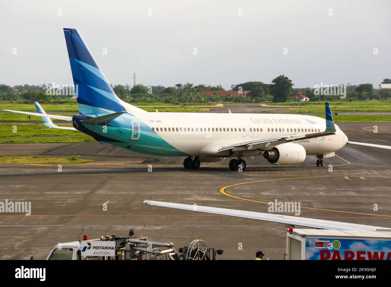 View of Garuda Indonesia airliner on runway at Juanda International Airport with clouds in blue