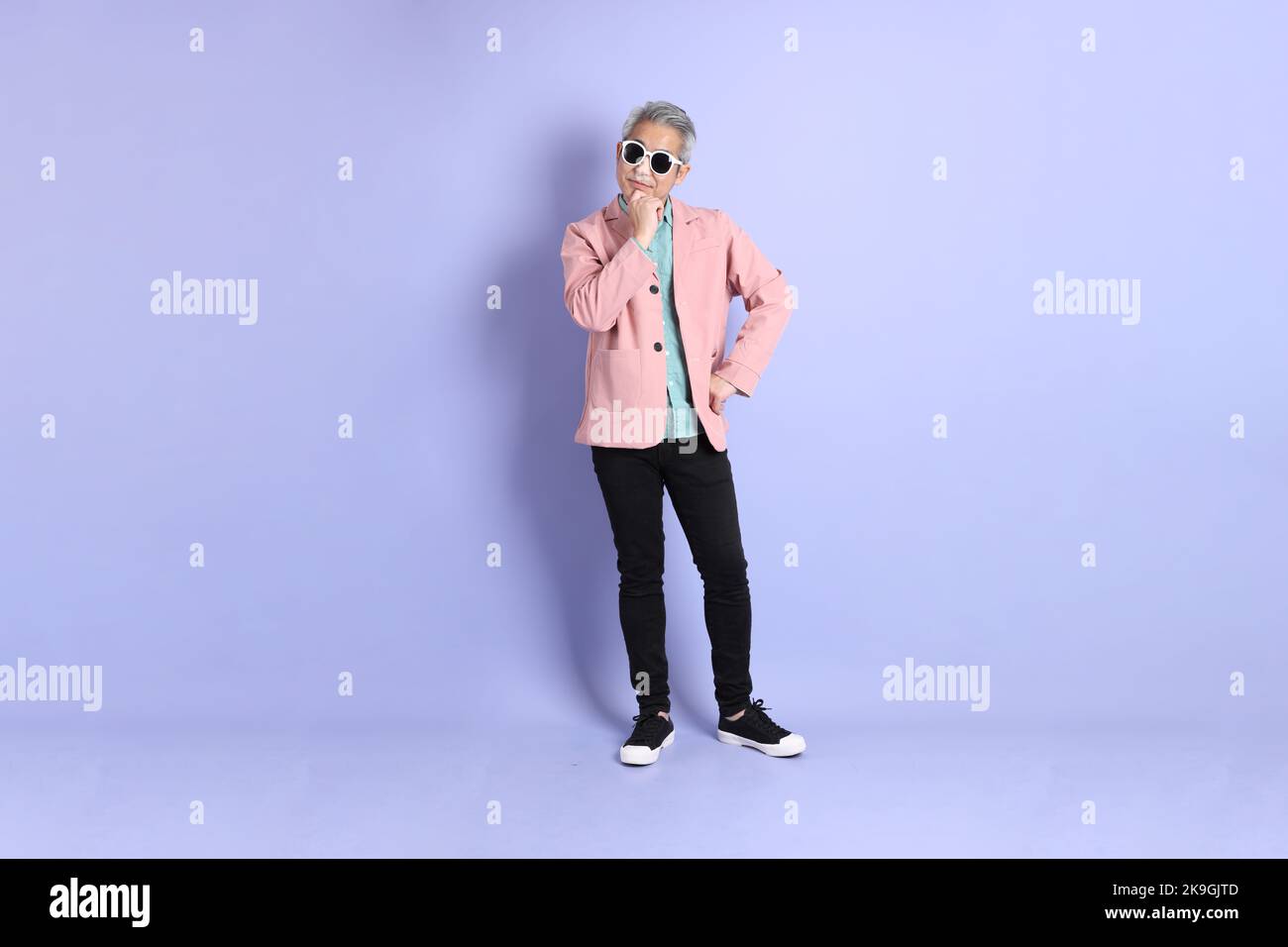The 40s adult Asian man stnading on the purple background with smart casual clothes. Stock Photo