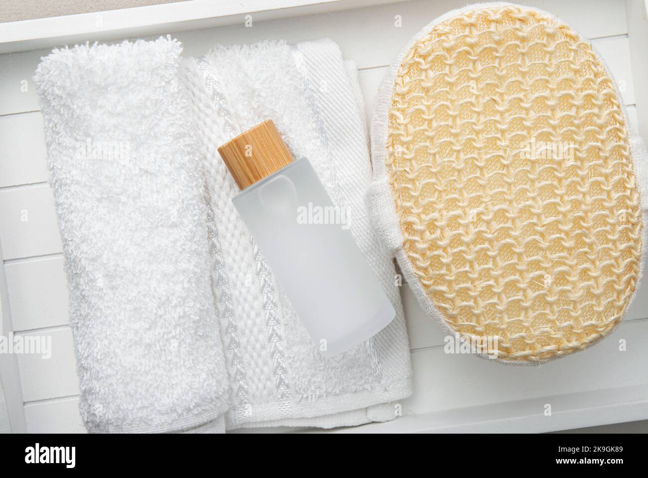 Concept of intimate wash gel for daily hygiene of the delicate intimate area. Matte soap bottle with gel on rolled white towel and bath sponge at home. Stock Photo