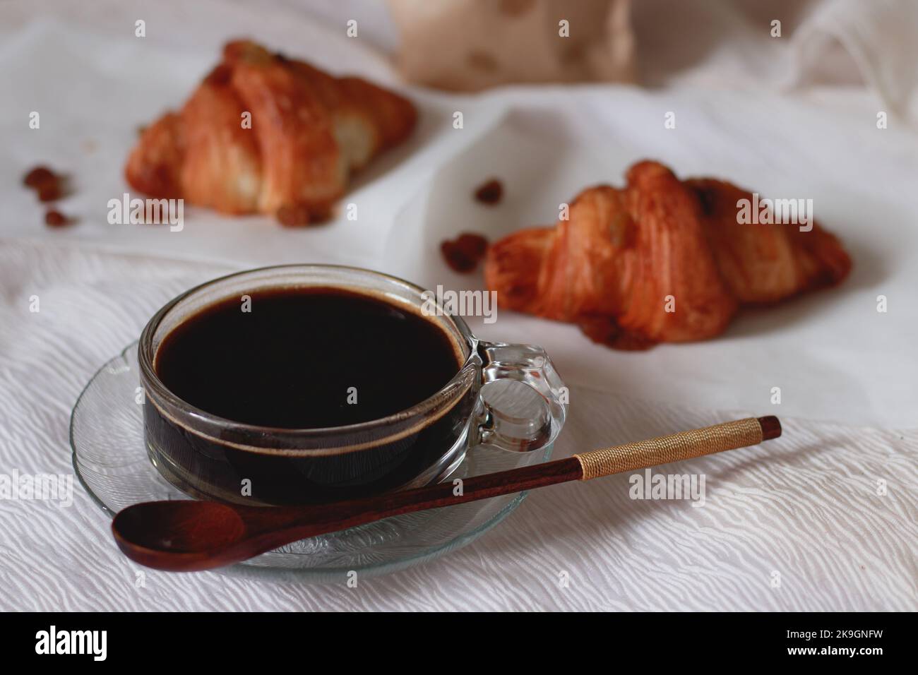 Selective focus to a cup of black coffee and freshly baked croissant for a simple french breakfast Stock Photo