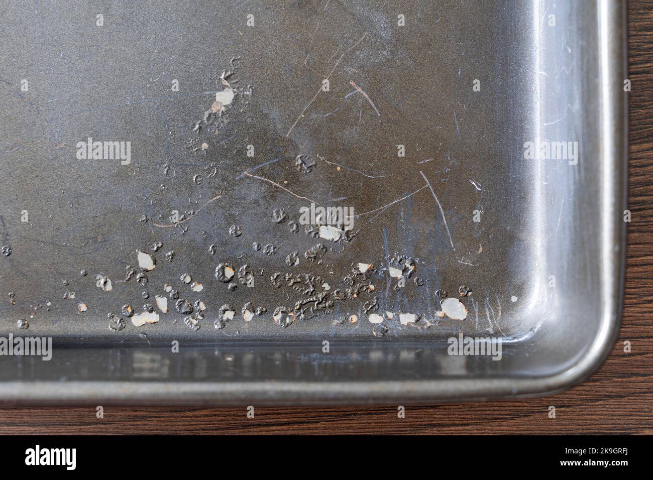 Chipped teflon PTFE (polytetrafluoroethylene) non stick coating on a baking tray. UK. PTFE is persistent in the environment, a 'forever chemical' Stock Photo