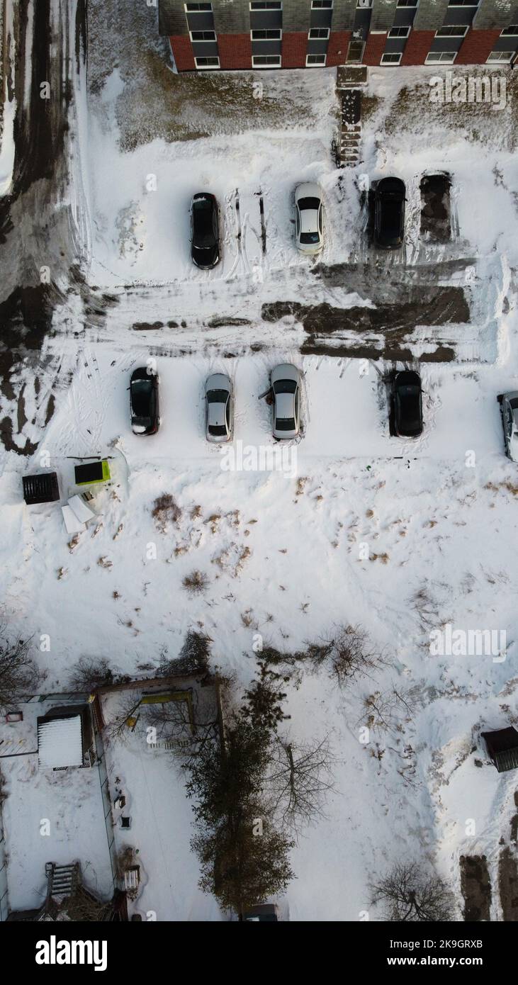 An aerial top view of a snowy yard with the cars parked, a vertical ...