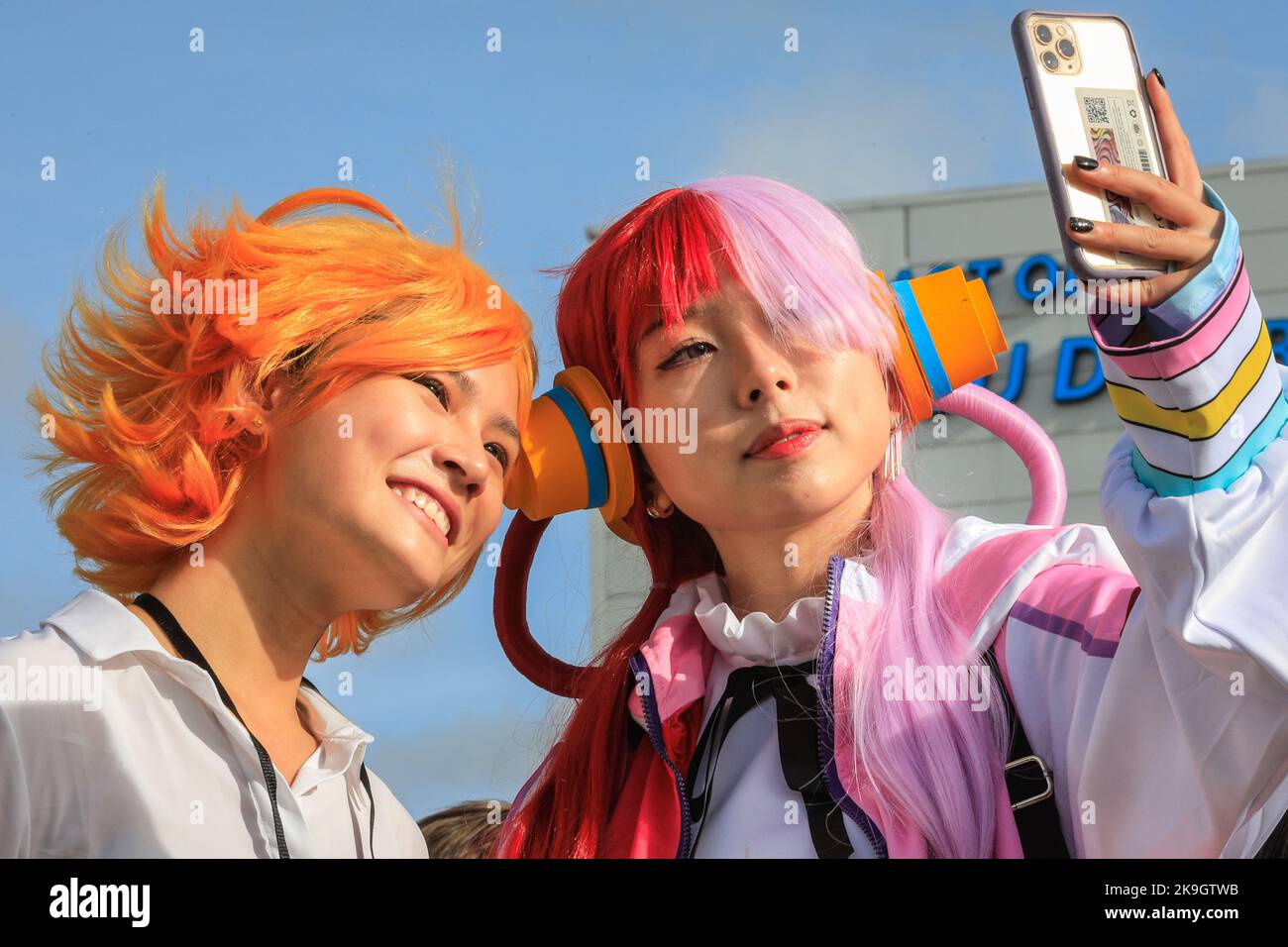 London, UK. 28th Oct, 2022. Two visitors as Emma from The Promised Neverland (left) and Uta from the One Piece anime, take selfies in the sunshine. Cosplayers, fans of anime, films and other visitors, most of them in costume, enjoy the opening day of MCM Comic Con at Excel London. Credit: Imageplotter/Alamy Live News Stock Photo