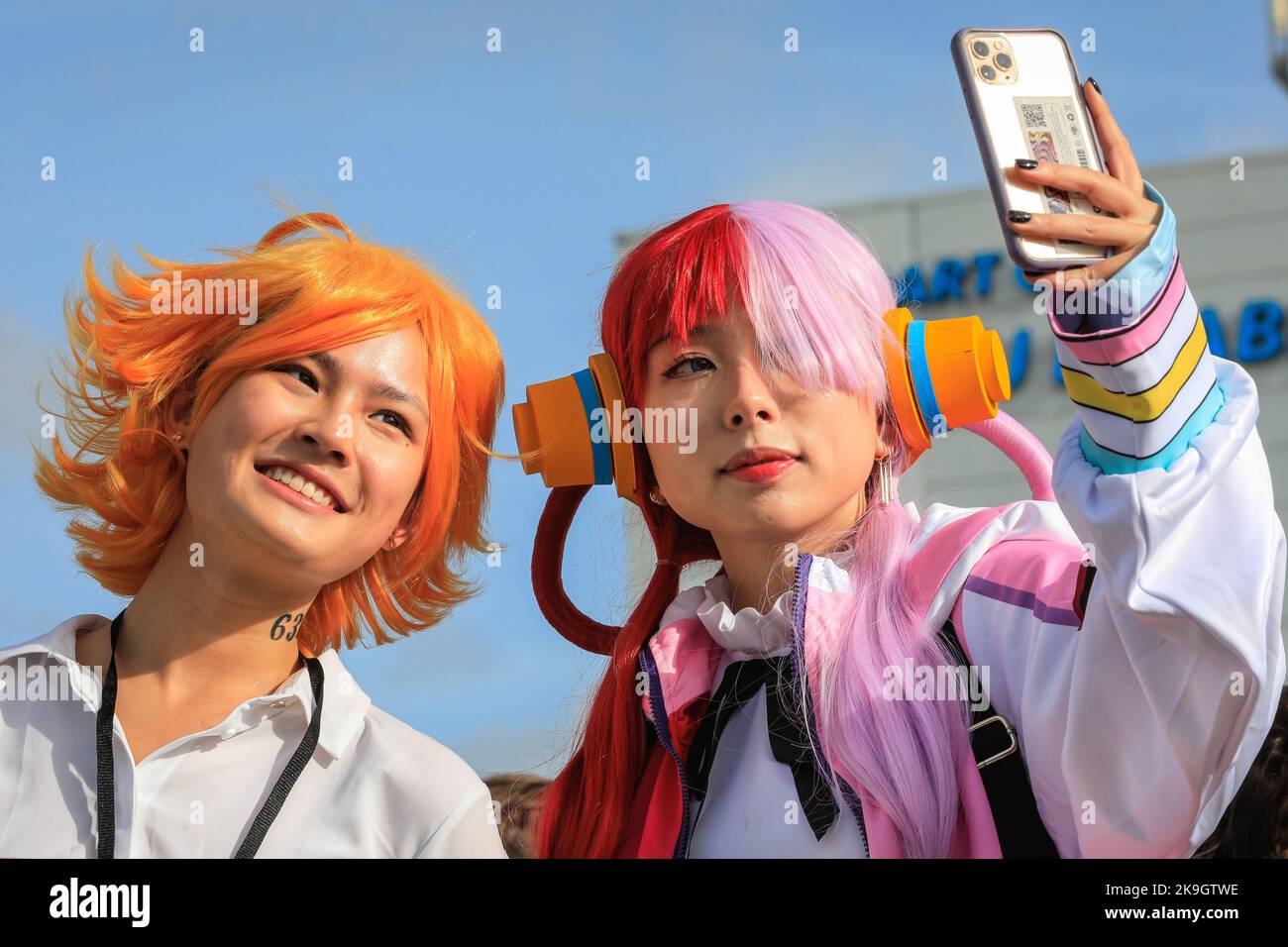 London, UK. 28th Oct, 2022. Two visitors as Emma from The Promised Neverland (left) and Uta from the One Piece anime, take selfies in the sunshine. Cosplayers, fans of anime, films and other visitors, most of them in costume, enjoy the opening day of MCM Comic Con at Excel London. Credit: Imageplotter/Alamy Live News Stock Photo