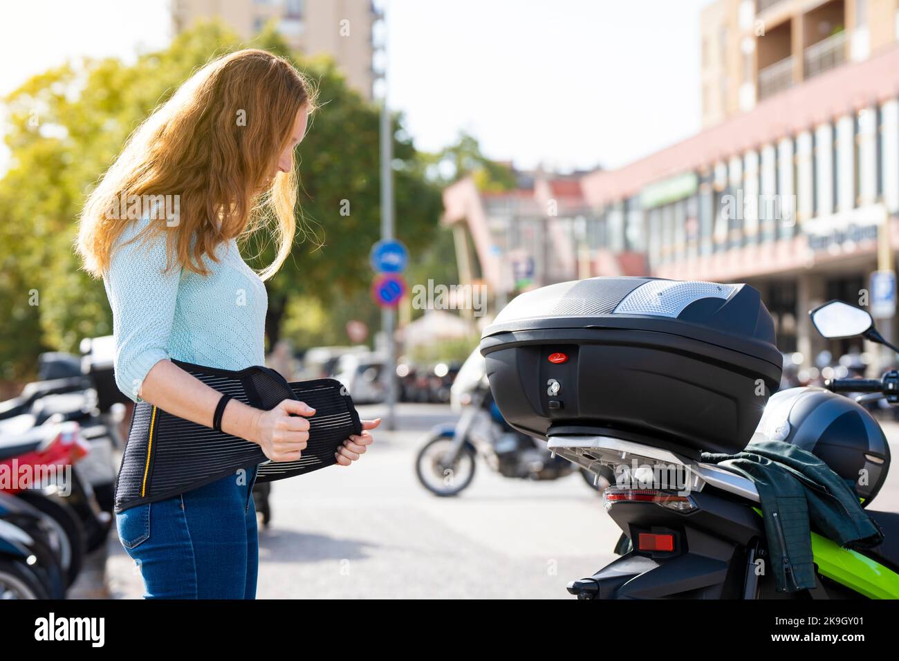 Redheaded woman puts on a girdle to ride a motorcycle Stock Photo