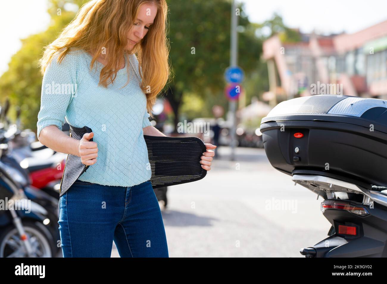 Redheaded woman puts on a girdle to ride a motorcycle Stock Photo