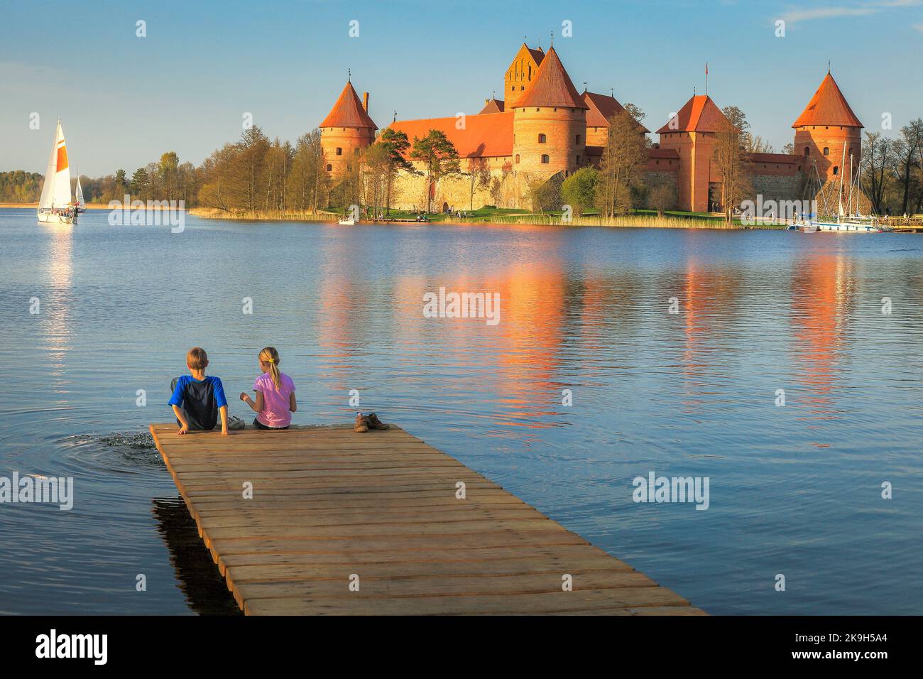Children playing on pier and Trakai Island with sailboat, Lithuania Stock Photo