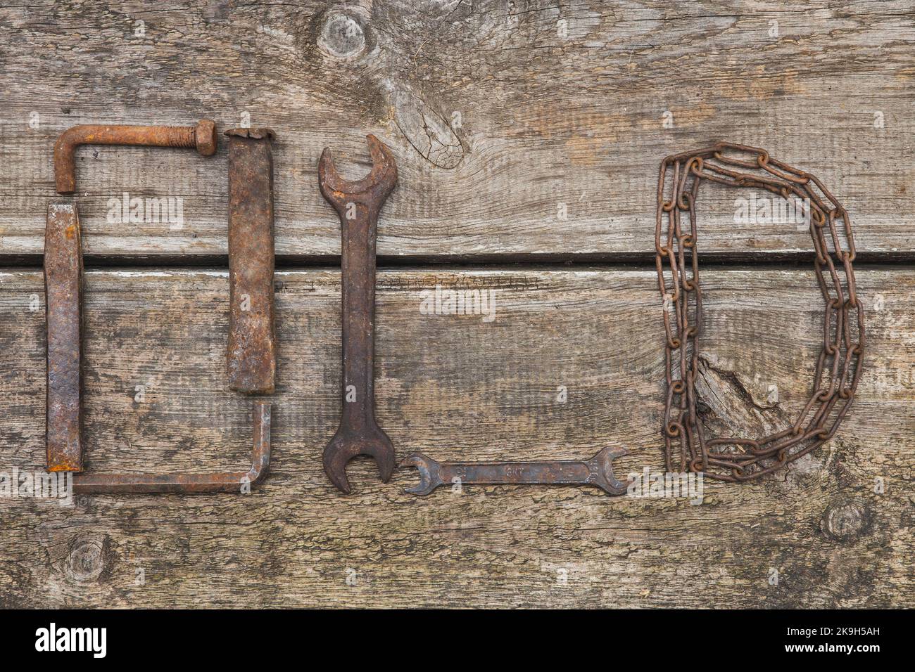 Word OLD made of rusty hand tools which lie on a rotten wooden table Stock Photo