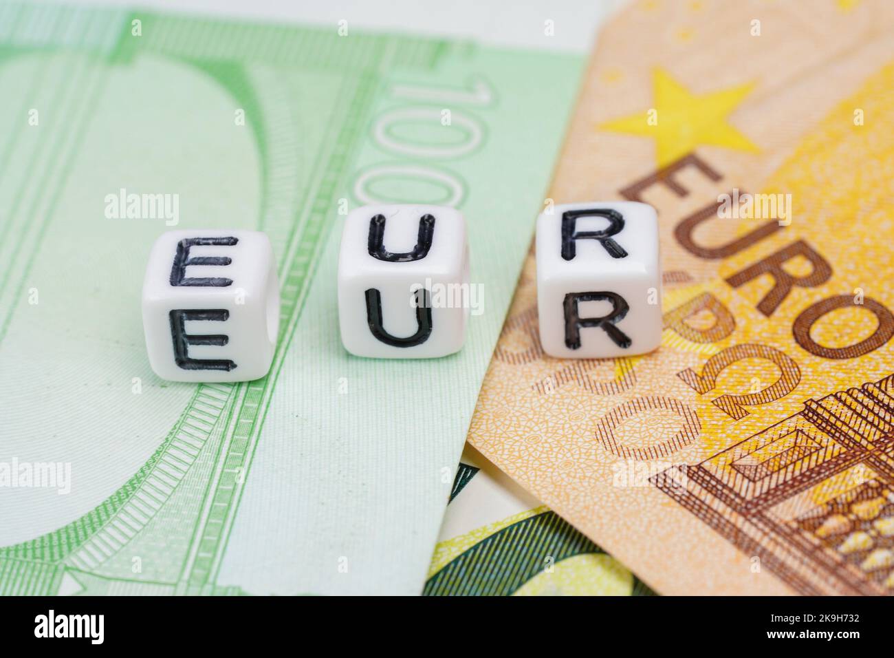 Small white beads with letters EUR on pile of euro banknotes, closeup detail Stock Photo