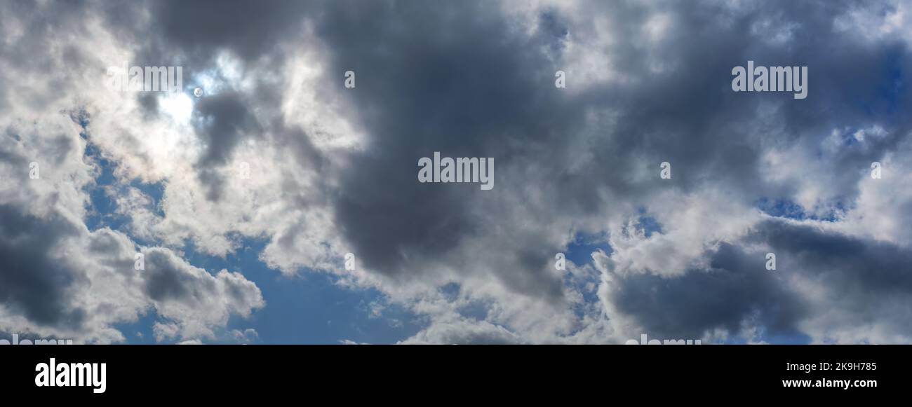 Sun shines through clouds on overcast sky - bright disc visible Stock Photo