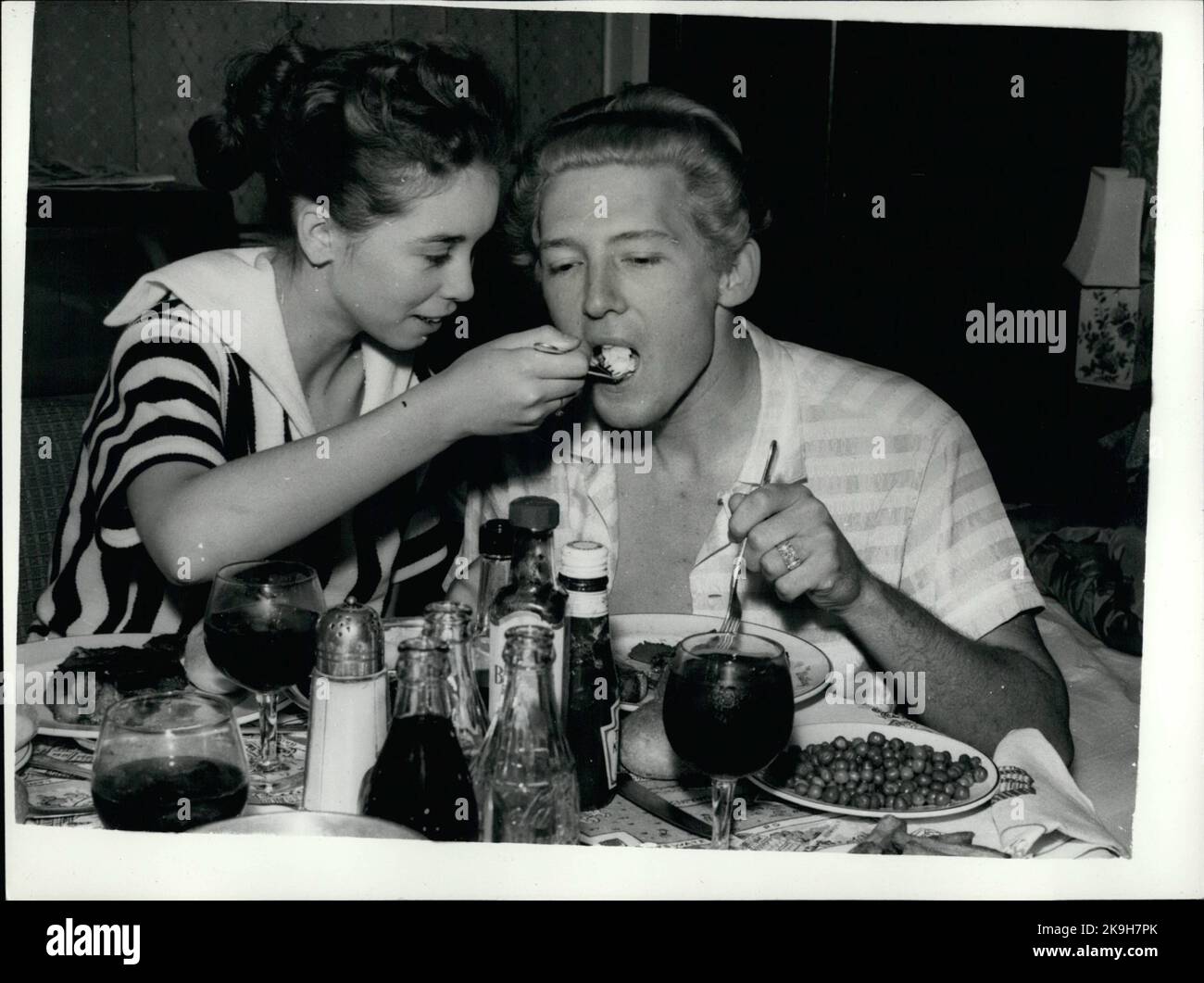 May 05, 1958 - Singer Jerry Lee Lewis and his child bride: Singer Jerry Lee Lewis may have to cut short his theatrical tour of Britain - because of the publicity over his thirteen year old bride. It has been said that the marriage to Myra took place before his divorce from his second wife had been obtained. When he appeared at the Granada, Tooting a crowd of teenagers stood outside the stage doot chanting ''We hate Jerry Lewis'', ''Baby snatcher'' and ''Watch him wheel his wife out in a pram''. Photo shows Myra the thirteen year old wife foods Jerry Lee Lewis in their hotel room last night. (C Stock Photo