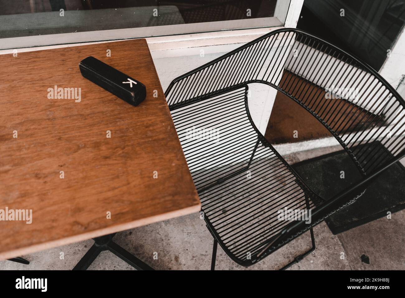 Glasses case on wooden table and metal chair outside a coffee shop ,George cafe, New Zealand Stock Photo