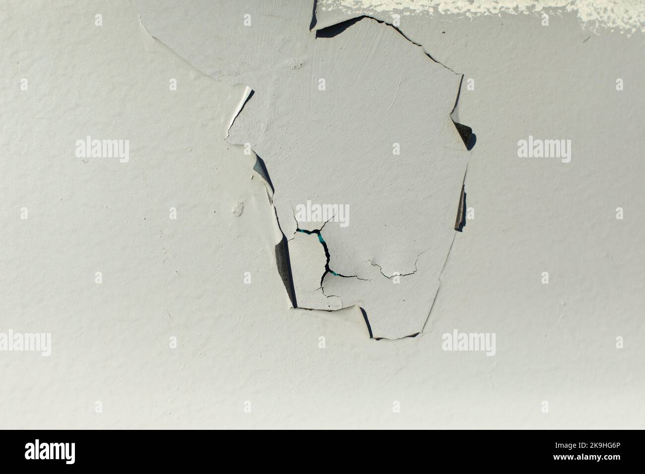 Old paint on wall. Grey wall texture. Poorly painted surface. Crack in