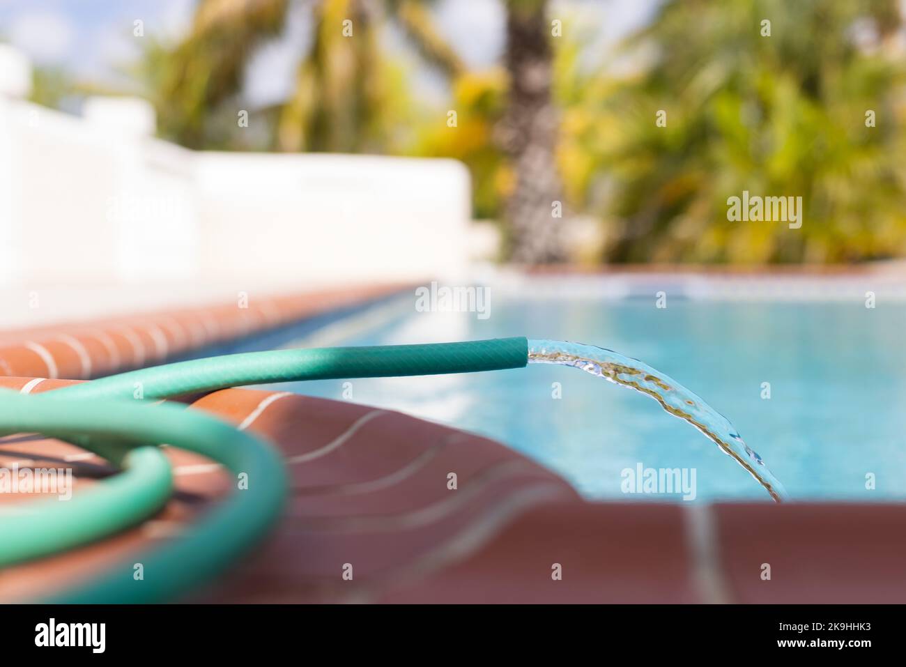Water pipe filling up swimming pool closeup. Pool maintenance Stock