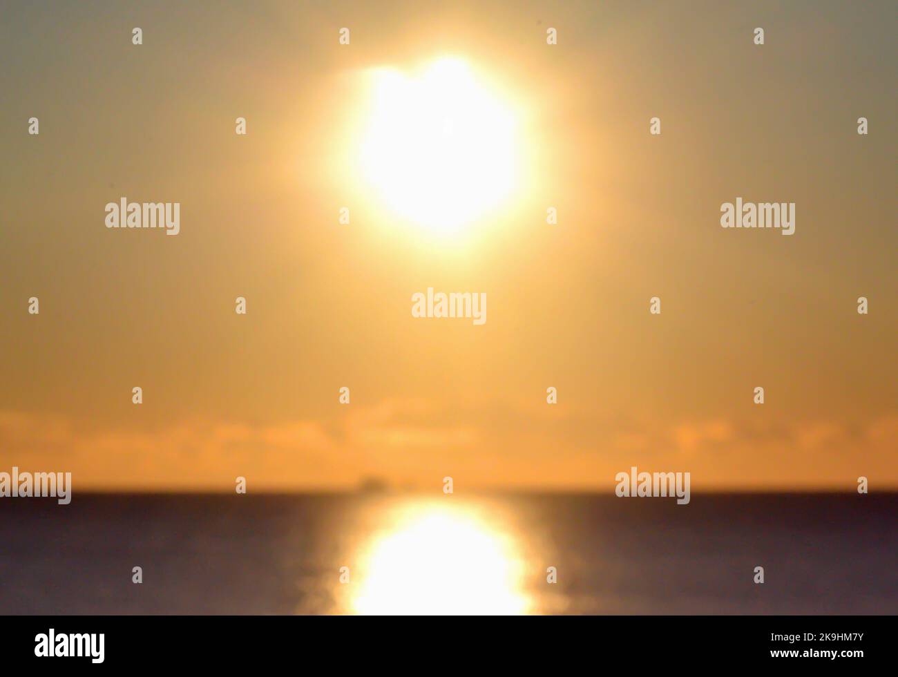Blurred background. The sun shining in the sky during sunset dawn. Sunrise dawning sundown. Sunny path, sunny walkway on the surface of sea waves. Sunlight. Sea landscape. Natural blurry bokeh texture Stock Photo