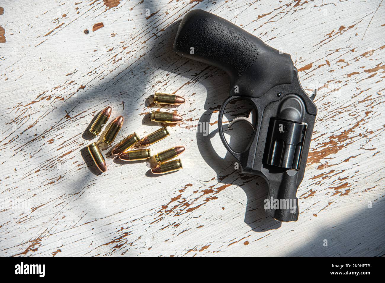 A black, Ruger, 9mm, snub-nosed revolver and a grouping of 9mm bullets. Stock Photo