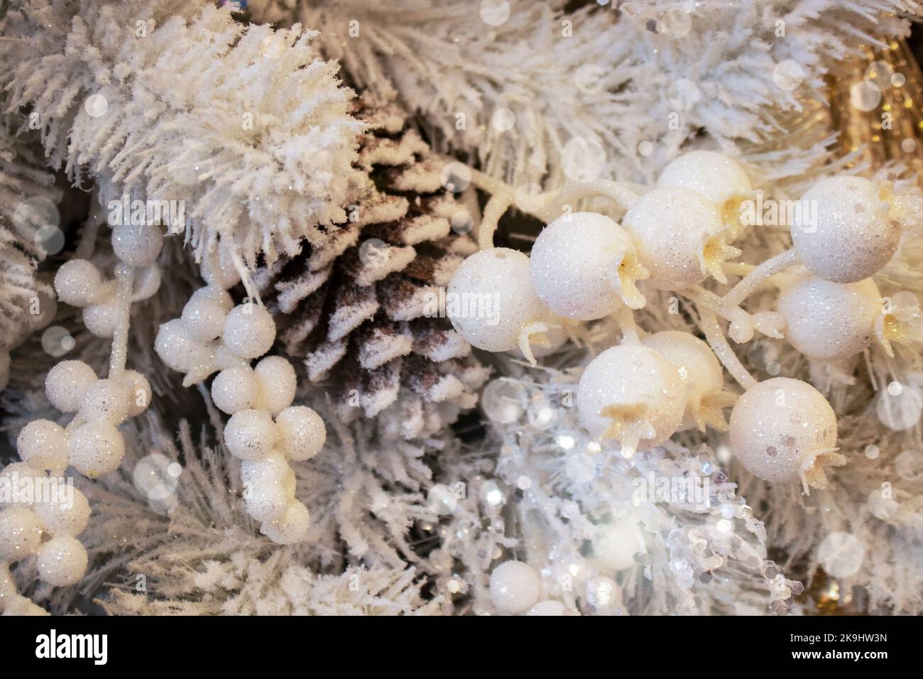 Christmas background of white sparkly berries and snow covered pine cones with bokeh and lens flare - white and gold Stock Photo