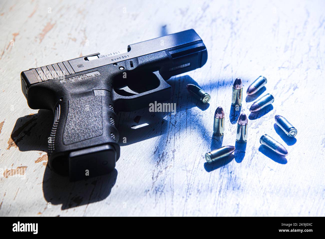 A Glock 19 pistol, manufactured in Austria, lies on a table along with several cartridges of 9mm