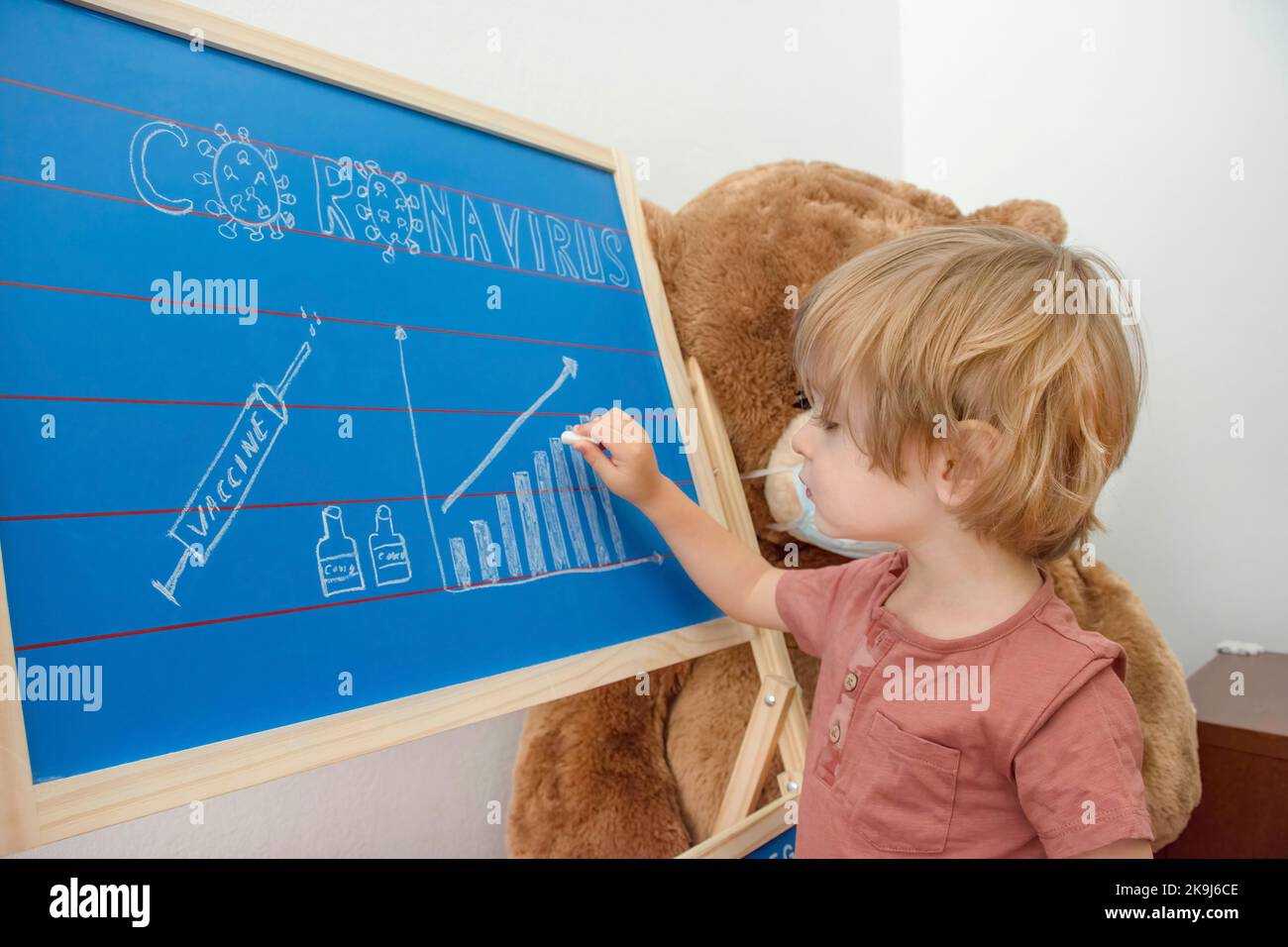 Cute child boy in home quarantine drawing the growing graph of COVID-2019 cases on a chalkboard, during coronavirus pandemic lock down Stock Photo
