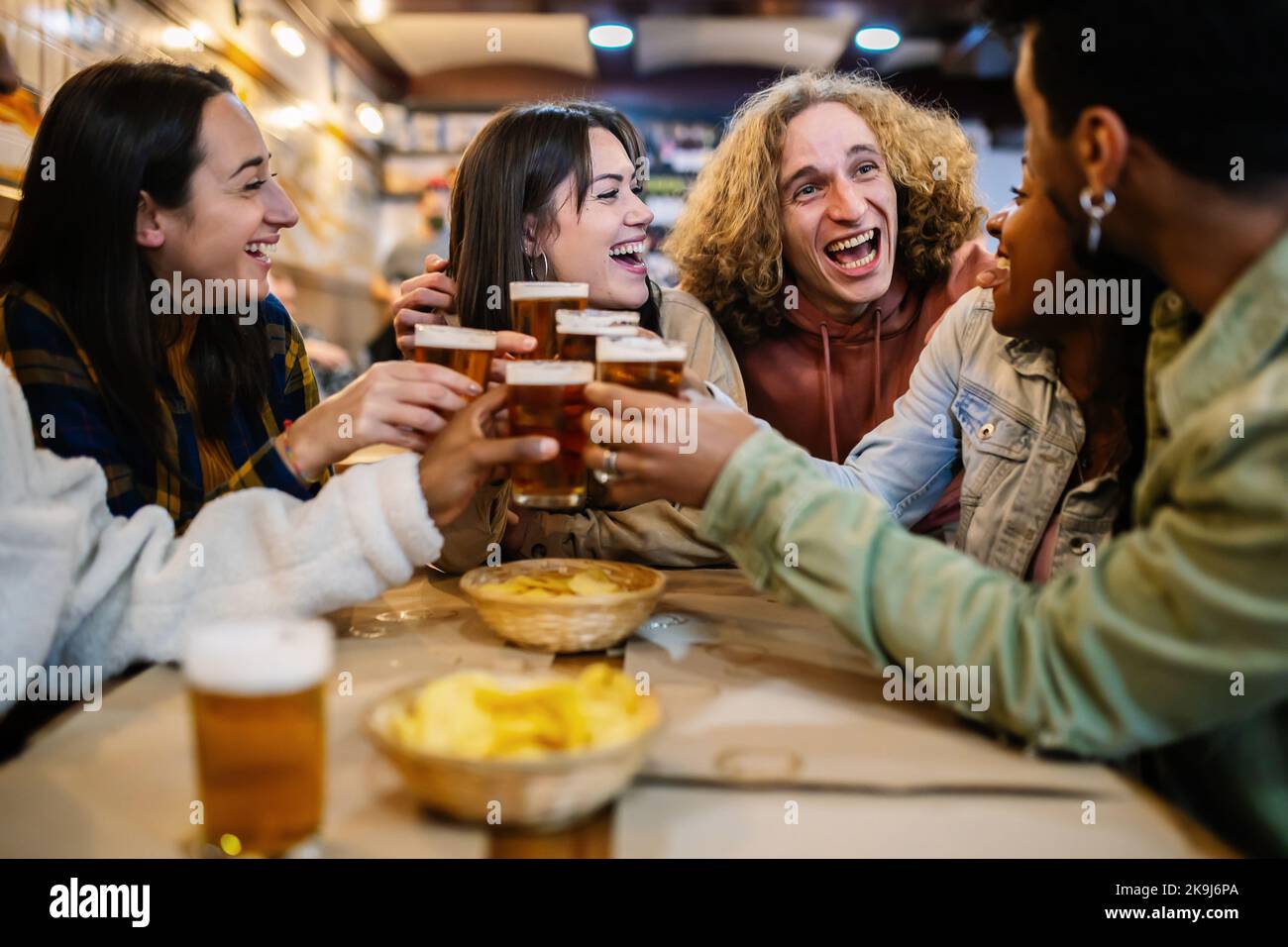 Young group of diverse best friends toasting beer in a bar Stock Photo