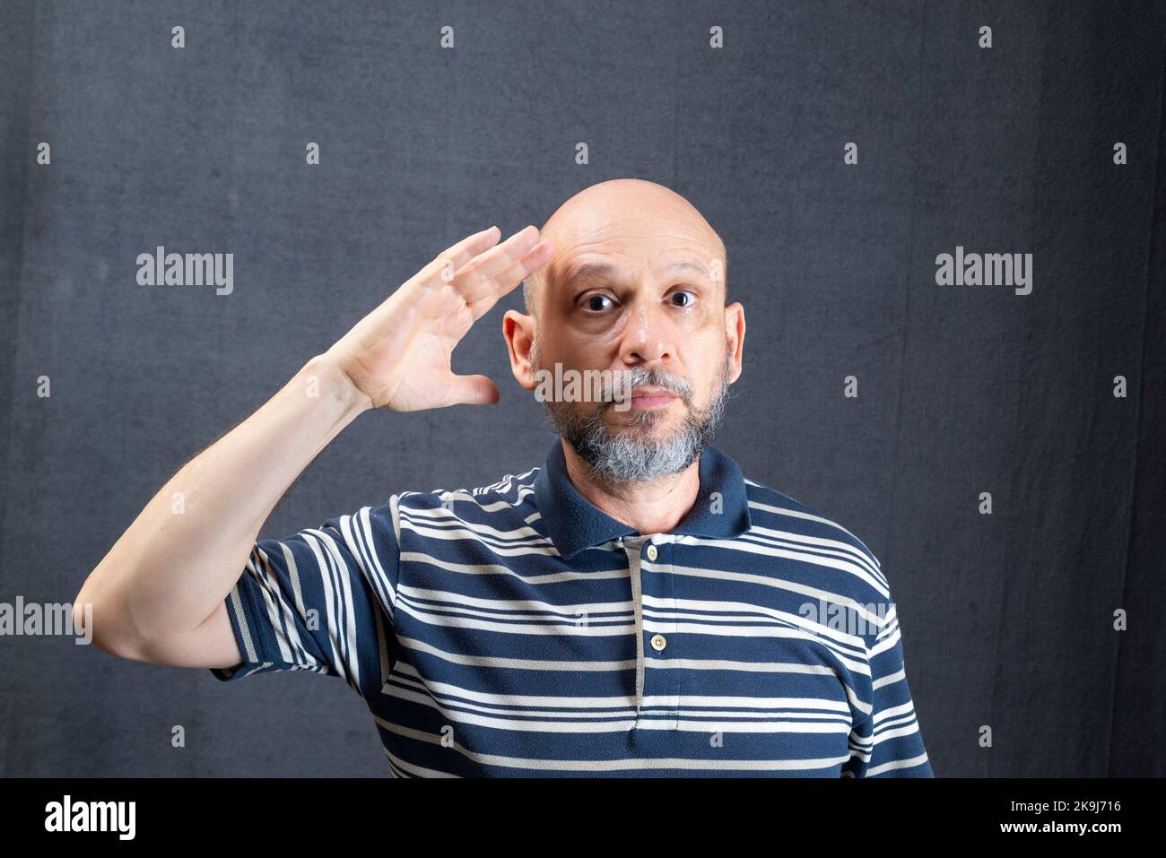 Cheerful funny young bearded business man in classic striped shirt standing making hand gestures. Isolated on gray background studio portrait. Achieve Stock Photo