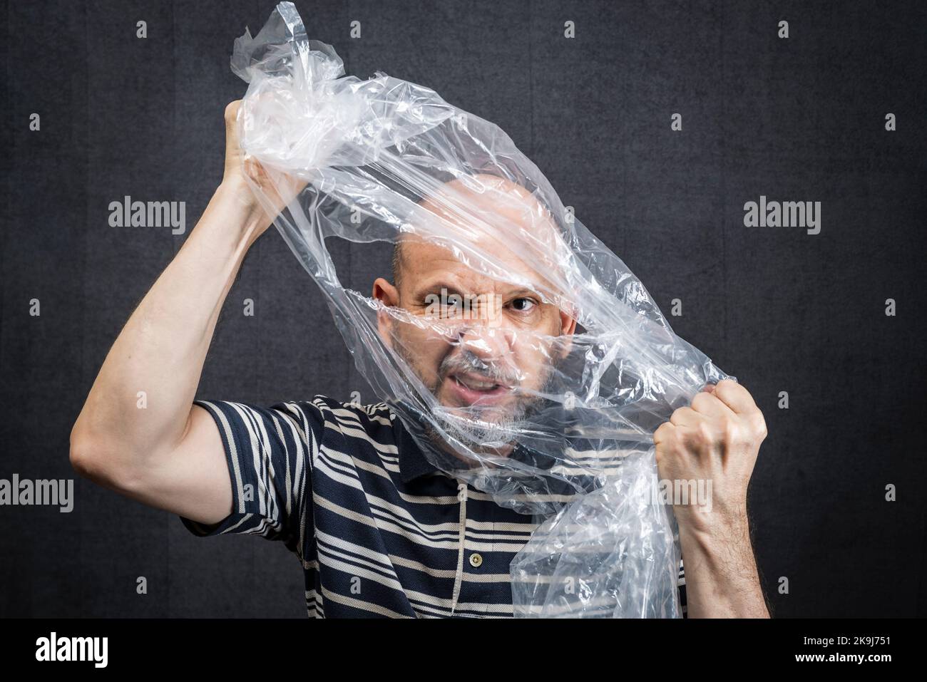 Mature man with a transparent plastic bag flying over his head and face. suffocate. face in a plastic bag, strangulation Stock Photo