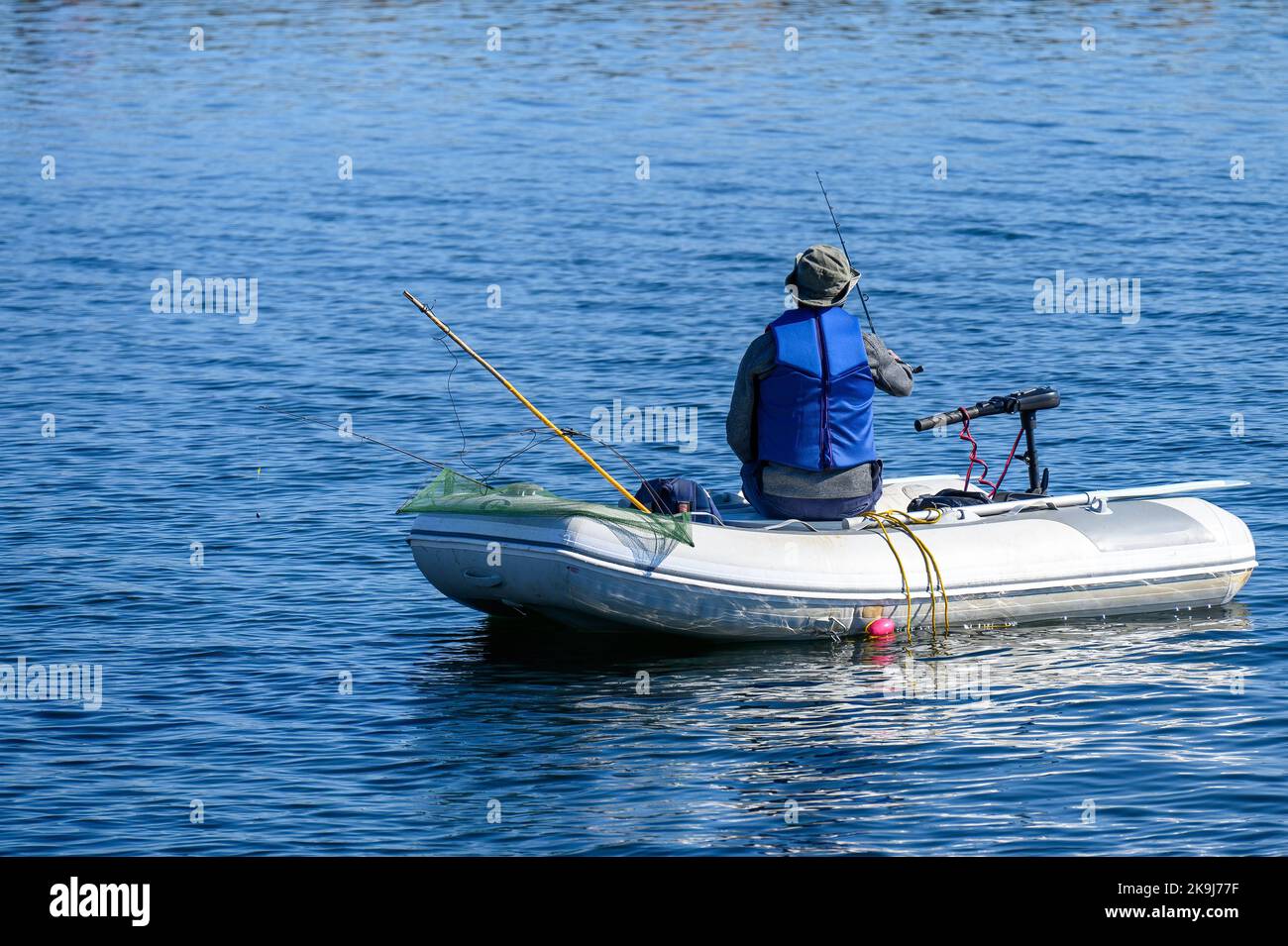 A lone man uses a rubber boat and a rod to fish in Lake Simcoe. Stock Photo