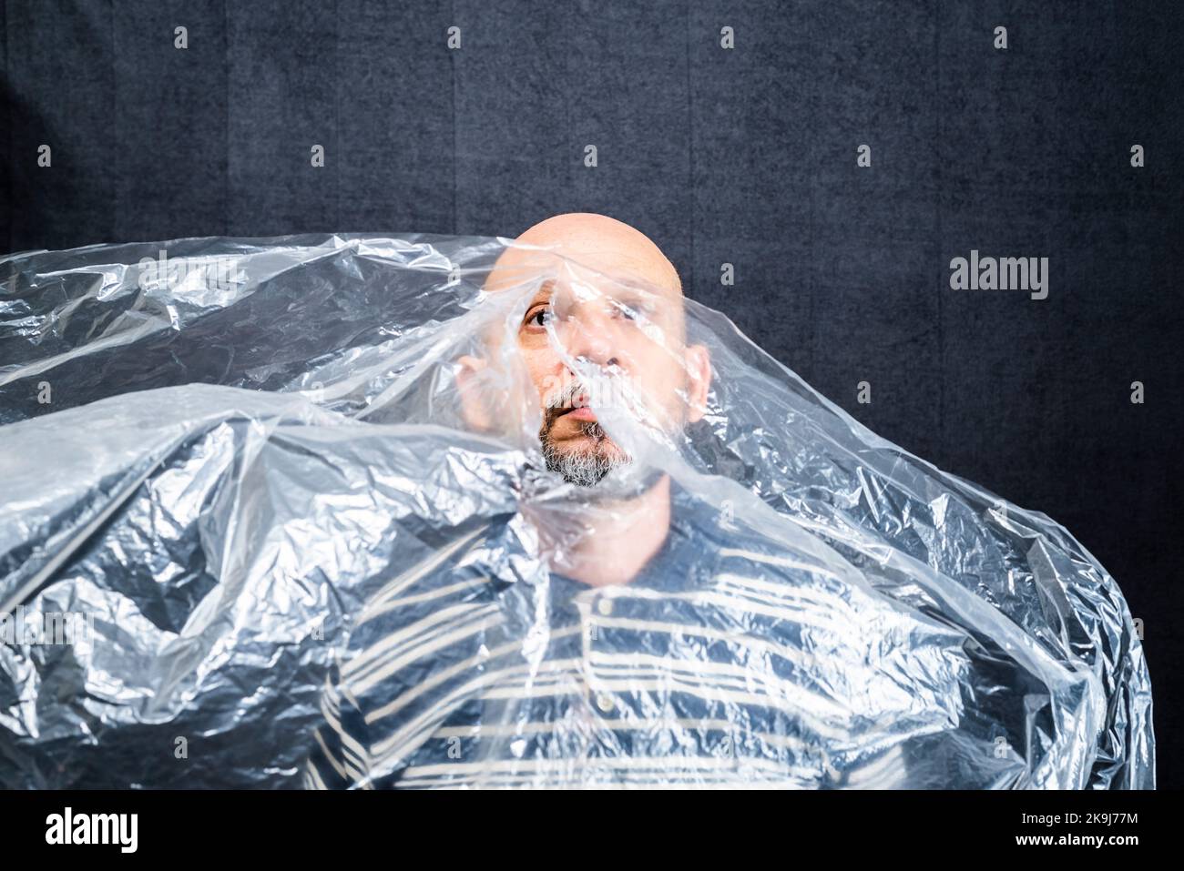 Mature man with a transparent plastic bag flying over his head and face. suffocate. face in a plastic bag, strangulation Stock Photo