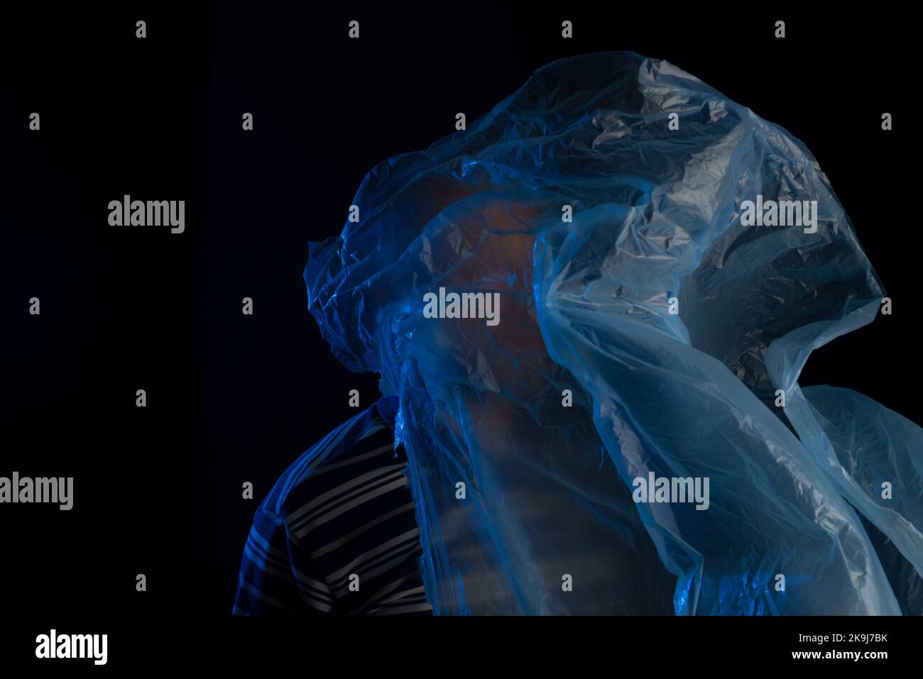 Mature man with a transparent plastic blue bag flying over his head and